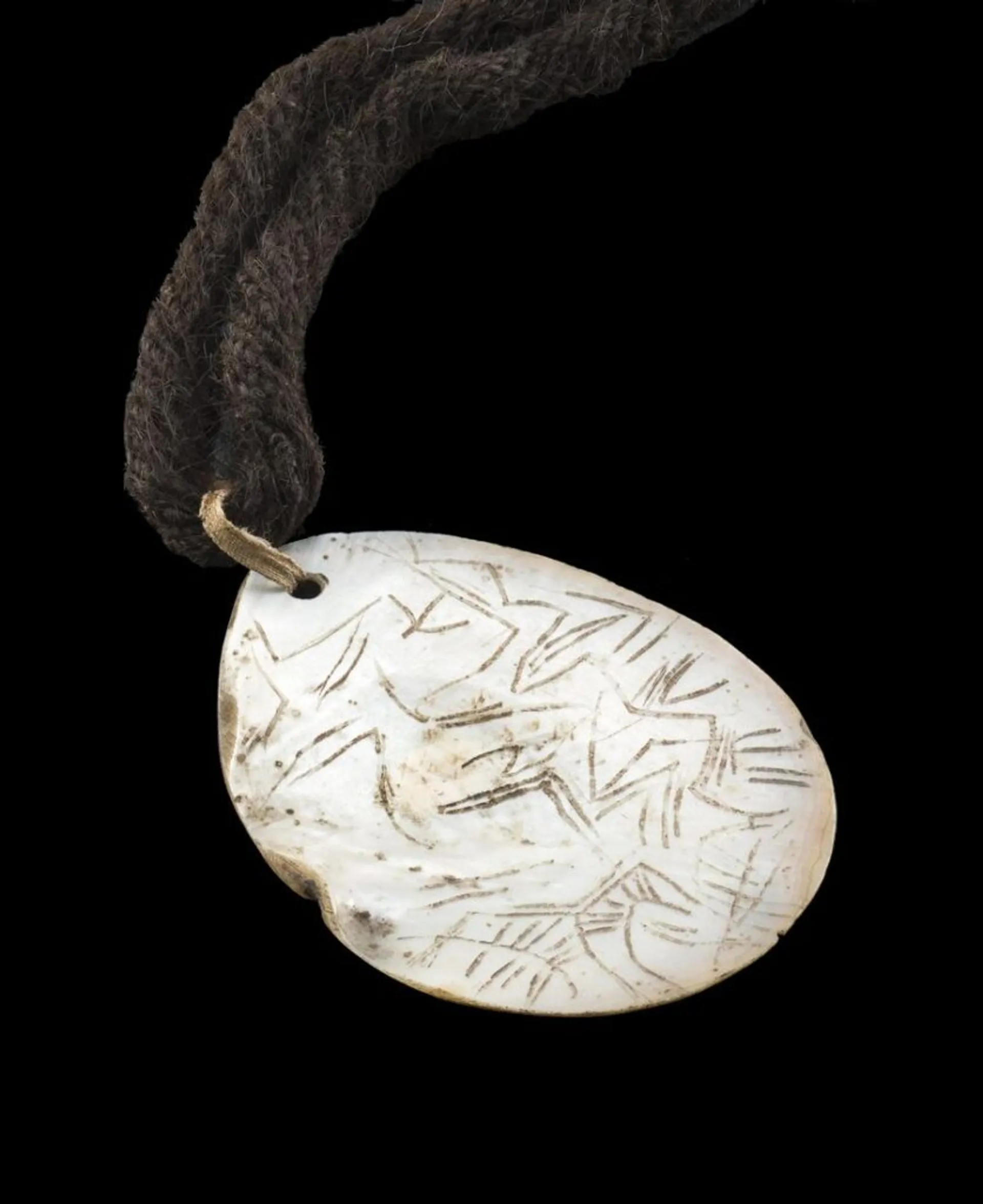 AN EARLY ENGRAVED PEARL SHELL PENDANT