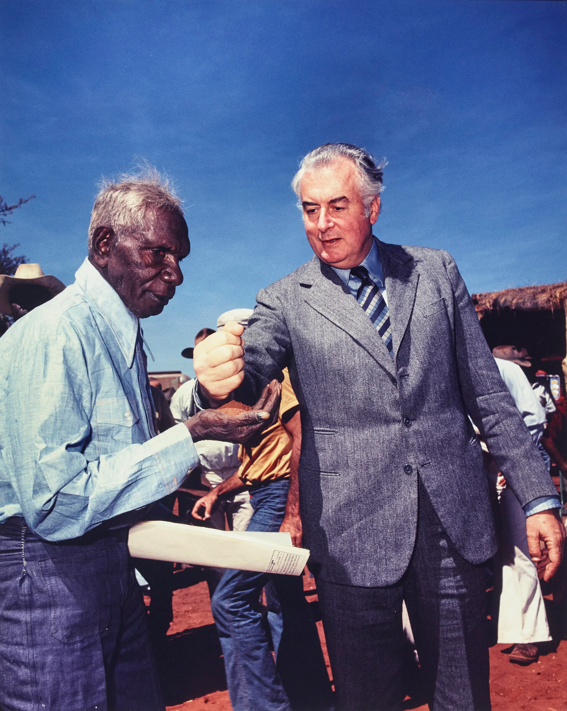 PRIME MINISTER GOUGH WHITLAM POURS SOIL INTO THE HANDS OF TRADITIONAL LANDOWNER VINCENT LINGIARI, NORTHERN TERRITORY
